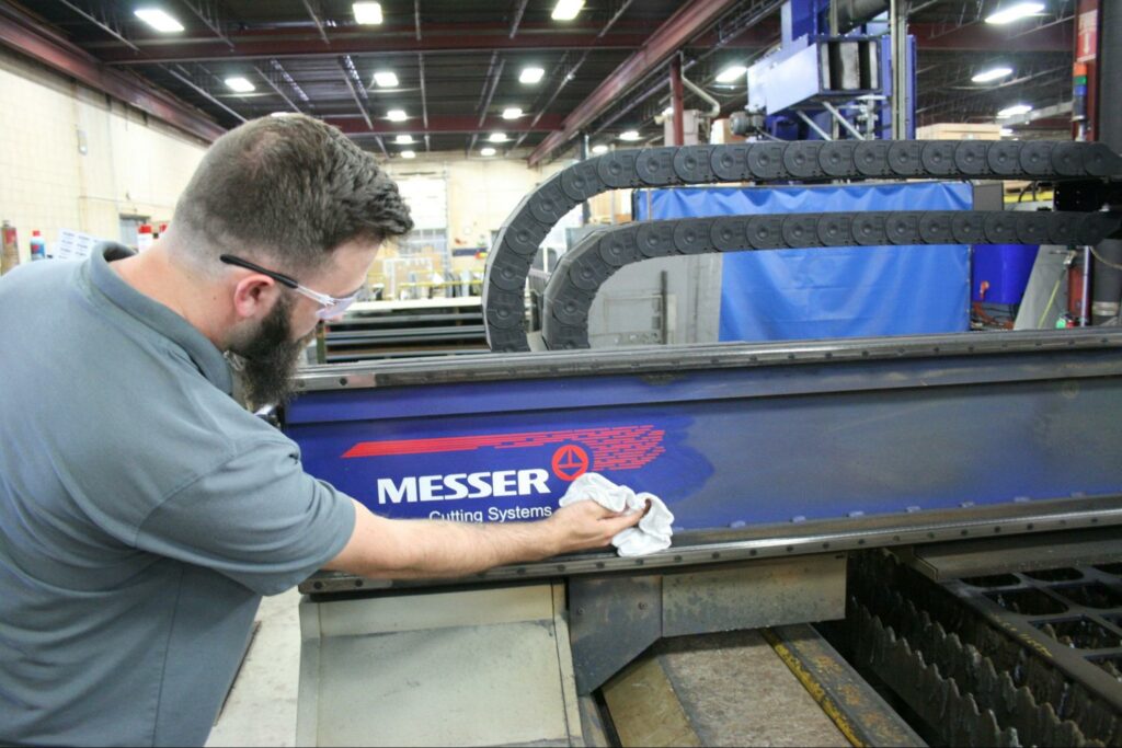 A Messer technician cleans and repairs a Messer cutting machine.